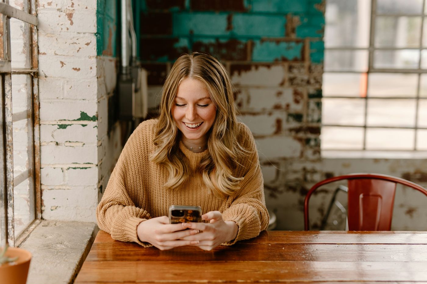 A smiling woman checking her phone at a table